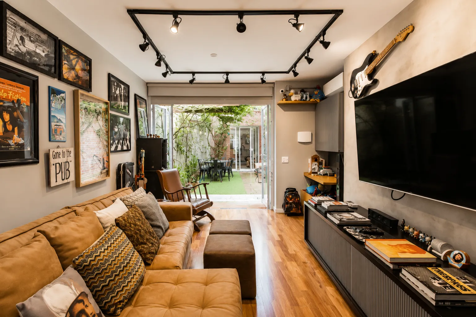 Living com sofá de couro caramelo, aberto para o jardim