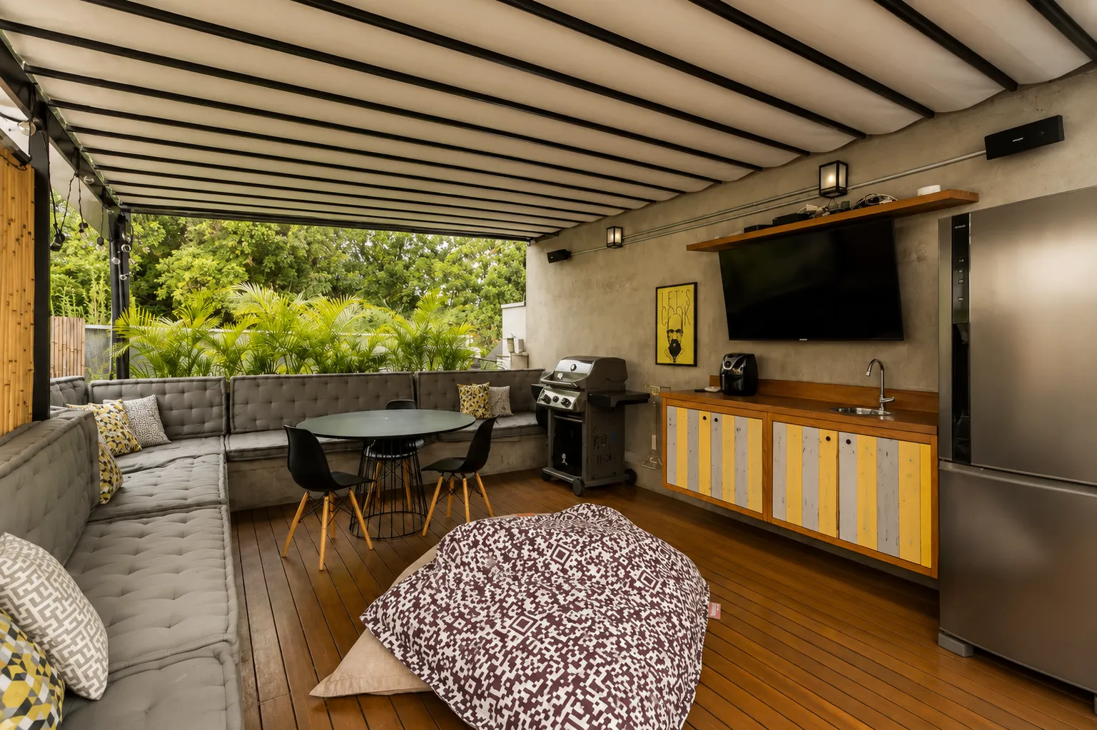 Lounge coberto do rooftop com sofá, mesa e churrasqueira